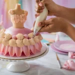 A close-up of a baker piping buttercream rosettes on a Barbie cake.